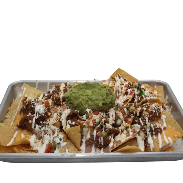 A tray of loaded nachos with pulled pork, cheese, sour cream, pico de gallo, and guacamole.