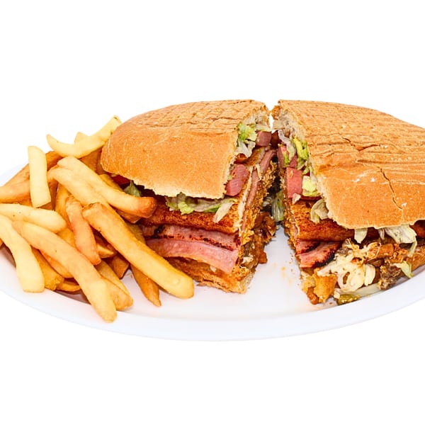 A large, sliced sandwich filled with various meats and lettuce, served with a side of french fries.