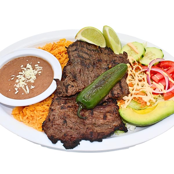 Grilled steak with rice, refried beans, salad, avocado, lime, and a jalapeño on a white plate.